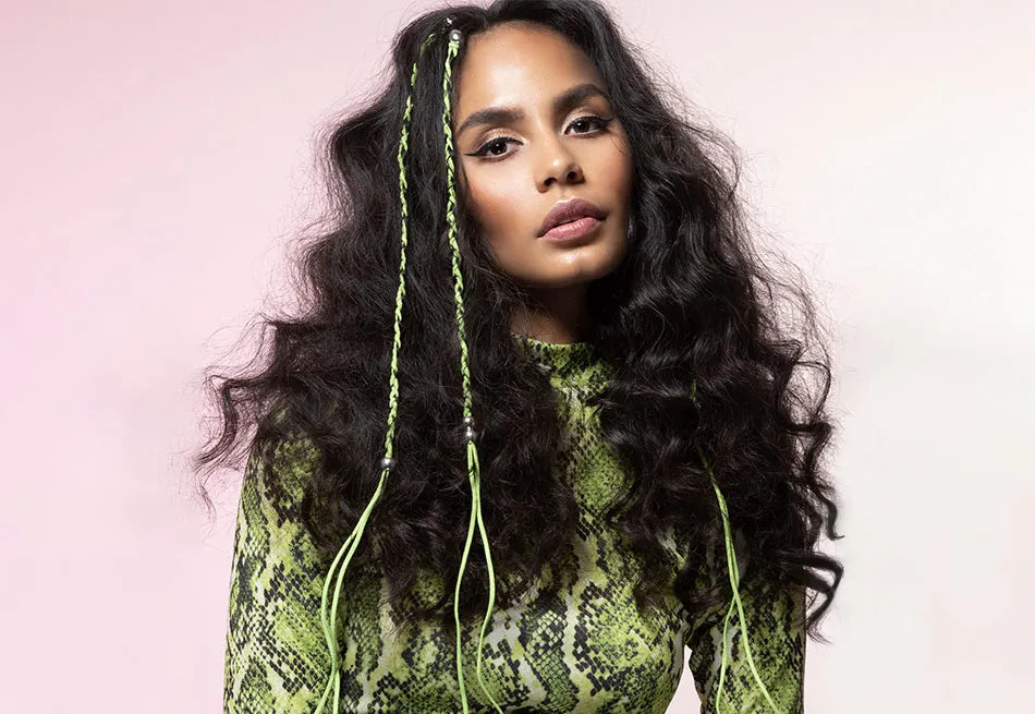 Model with black curly hair and 3 neon green braids.