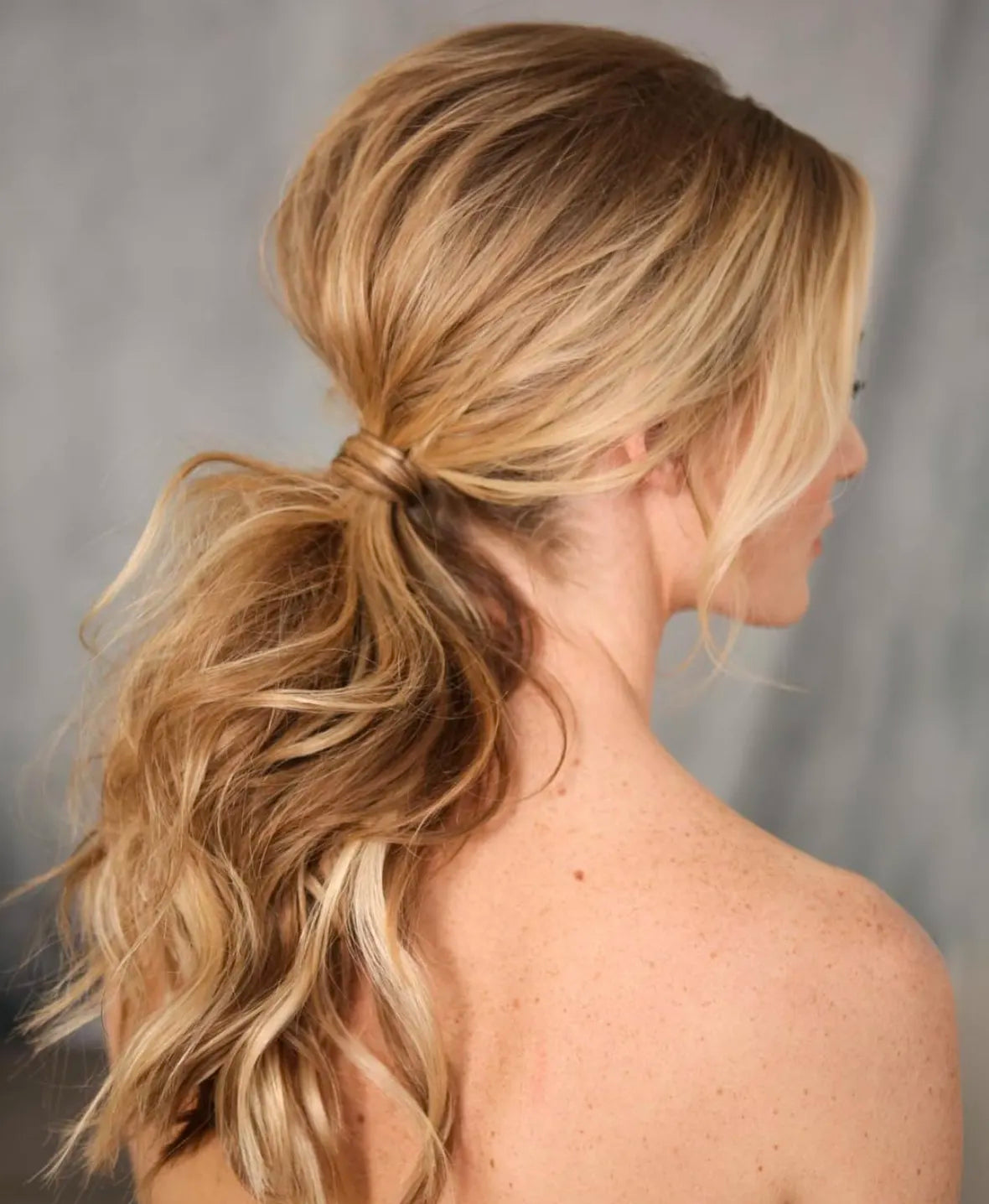 Blonde model showing off a low ponytail hairstyle.
