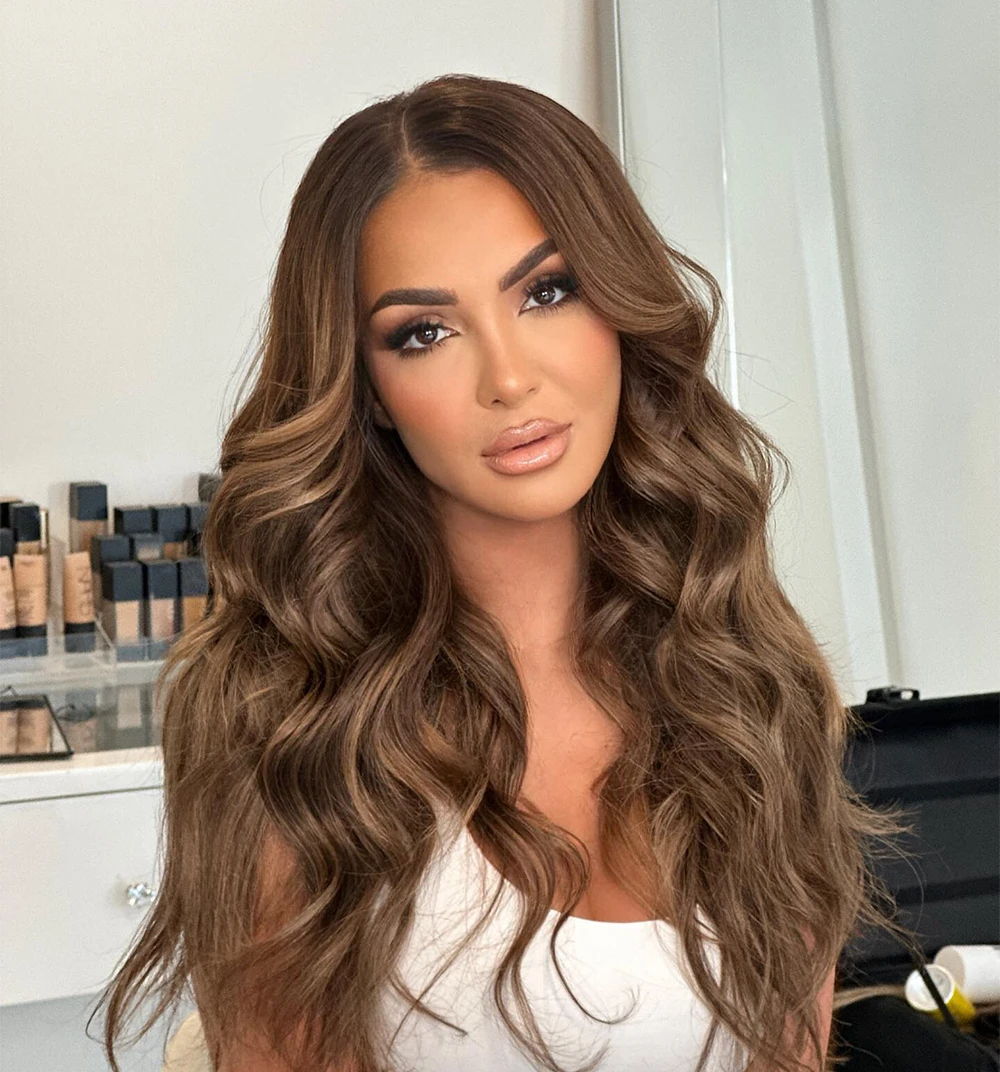 female model with long brown way hair in white tank top with full makeup