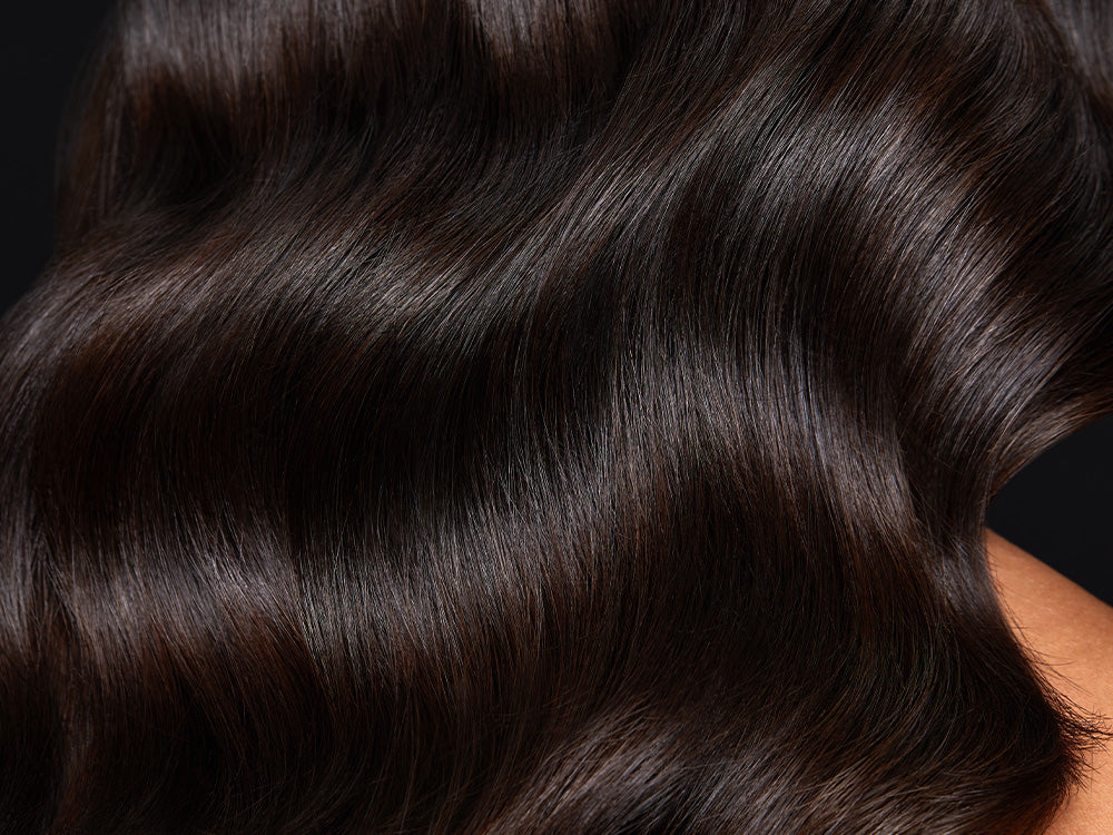 Image of model with arm under shiny and wavy black hair.