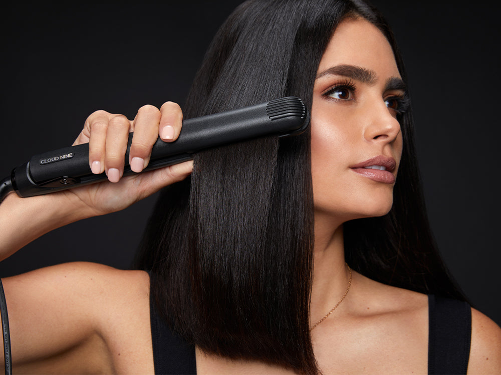 Model swipes a black Original Iron hair straightener through her black hair.