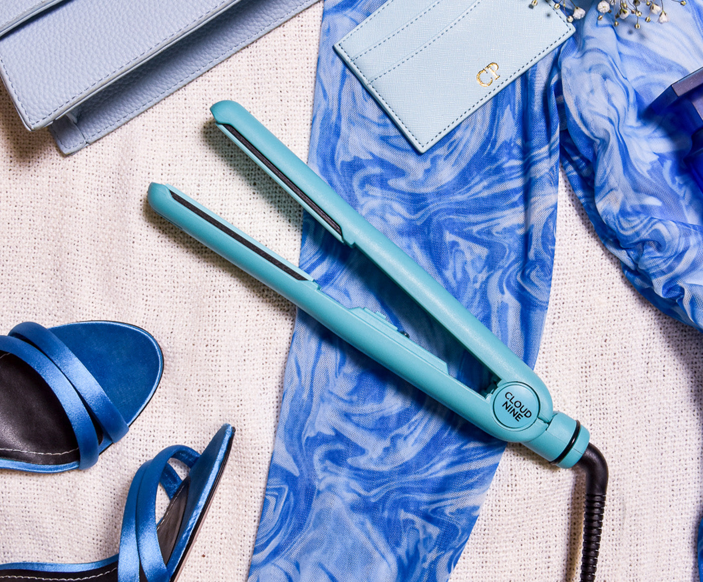 Soda Fountain Blue Retro Iron surrounded by other blue items including a blue pair of heels, a blue patterned pair of trousers and a blue purse.