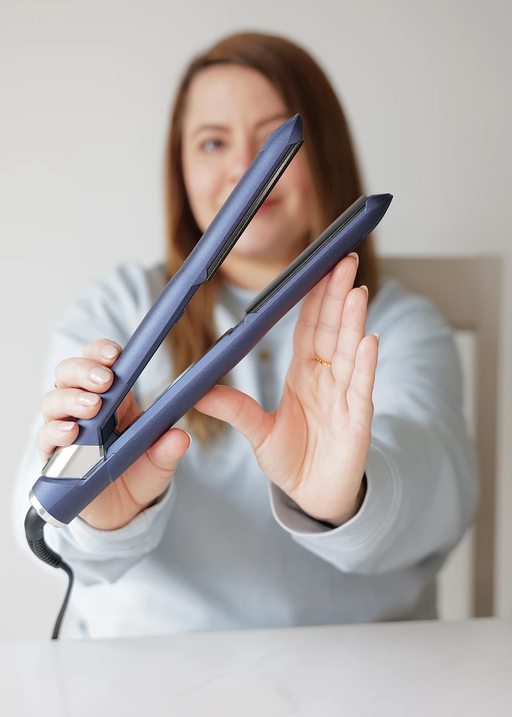 female influencer holding 2-in-1 Contouring Iron Pro in front of camera while placing hand against outside of plates