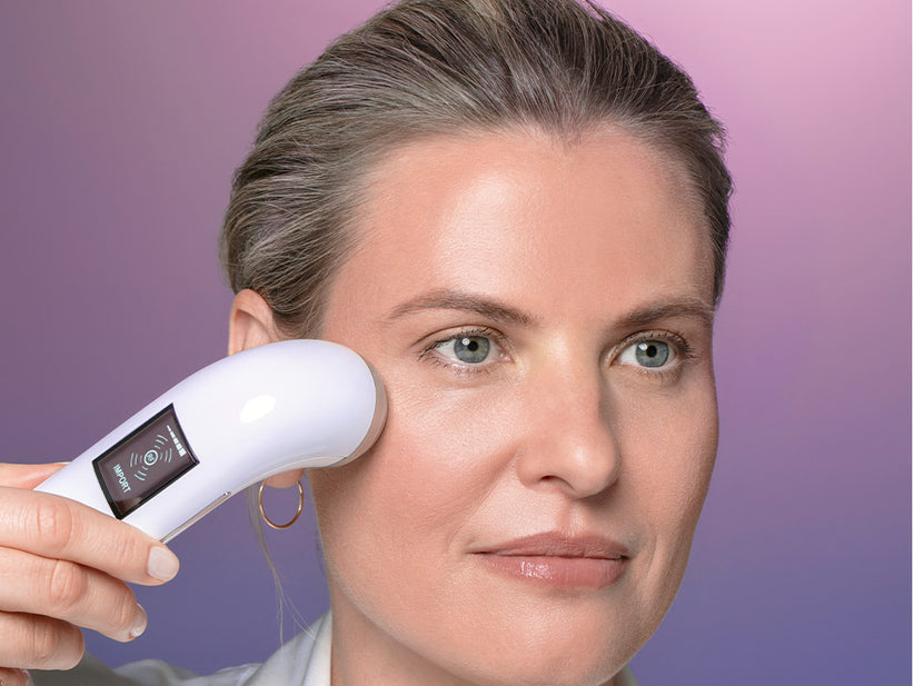white female using the rejuvenate beauty device on her face just below her eye 