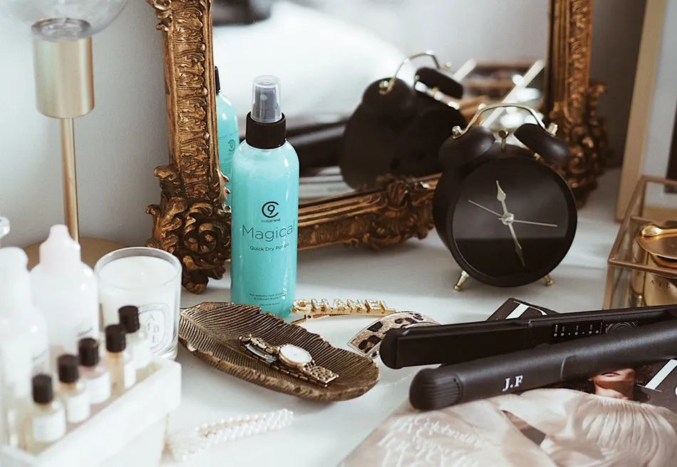 A bottle of Magical Potion set up on a dressing table. Featuring a mirror, a clock, some accessories and a monogrammed Original Iron.