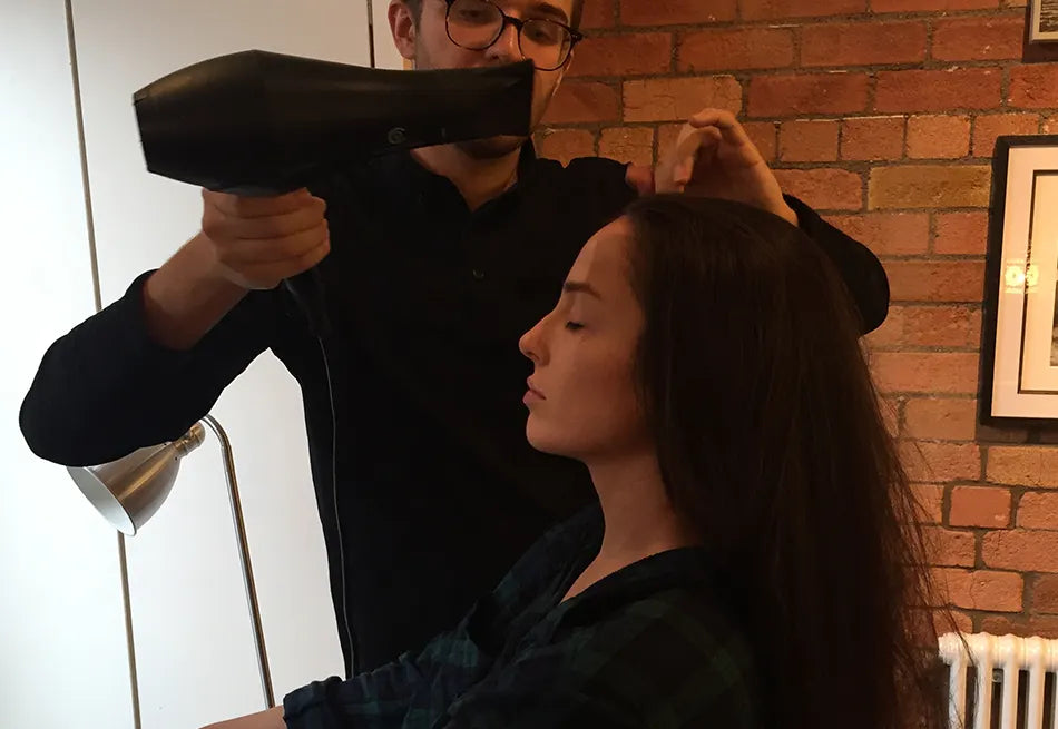 Hairdresser using The Airshot to dry the client's long brown hair.