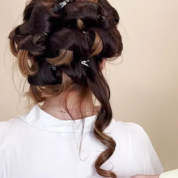 A model with their hair curled and clipped up. One curl is hanging down.