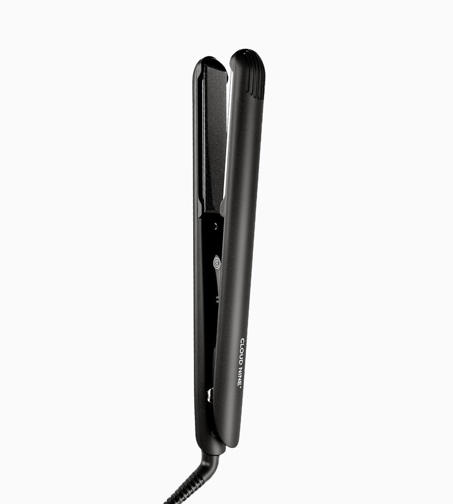 Full view of a black Touch Iron hair straightener standing vertical.
