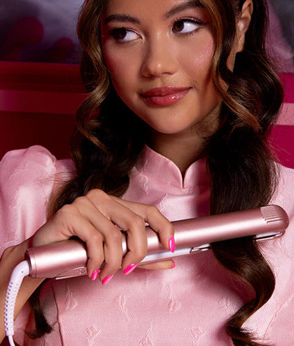 Model running a pink Original Iron Pro hair straightener through curled brunette hair.