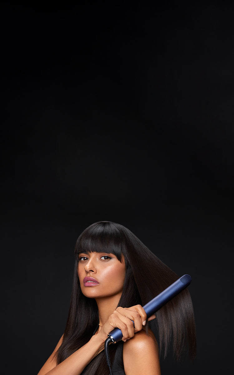 Model running the blue 2-in-1 Contouring Iron Pro through her black hair at the bottom of a black background.