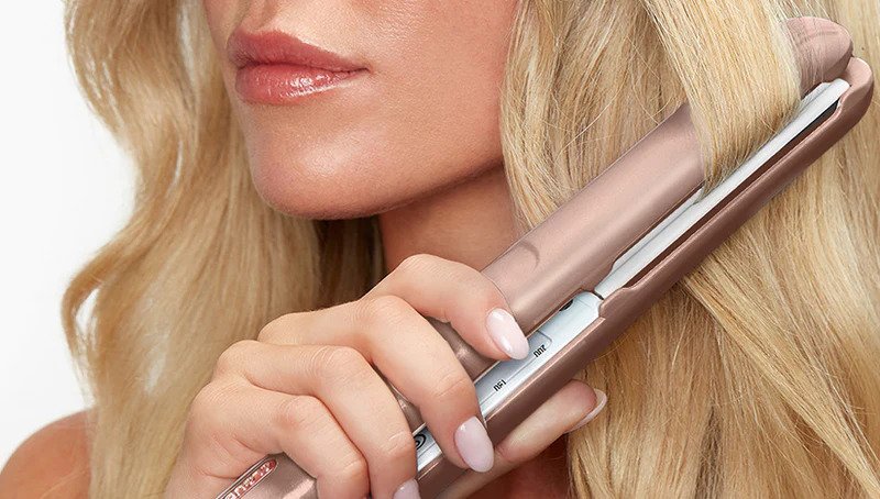 Blonde model using a pink Original Iron Pro hair straightener to wave hair.