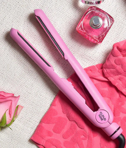A pink Retro Iron hair straightener on a pink towel with a pink rose and pink perfume bottle.
