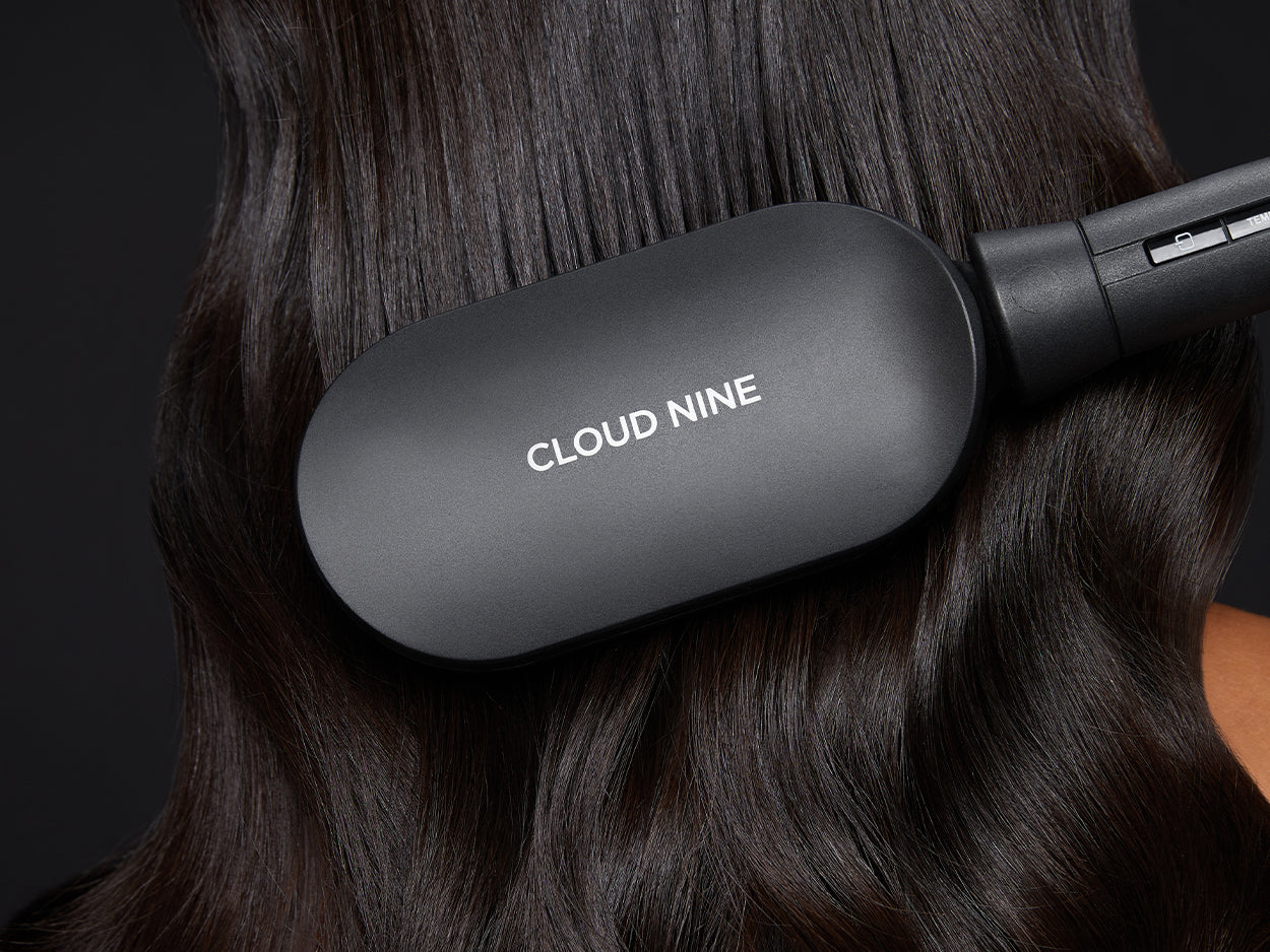 Close up of the Hot Brush straightening wavy hair. The CLOUD NINE logo is shown on the back of the brush.