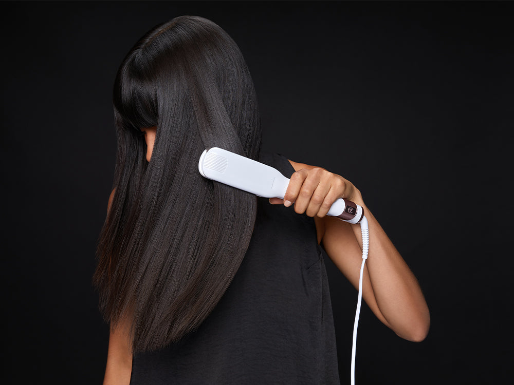 Model looking down as she swipes her long black hair with a white Wide Iron Pro.