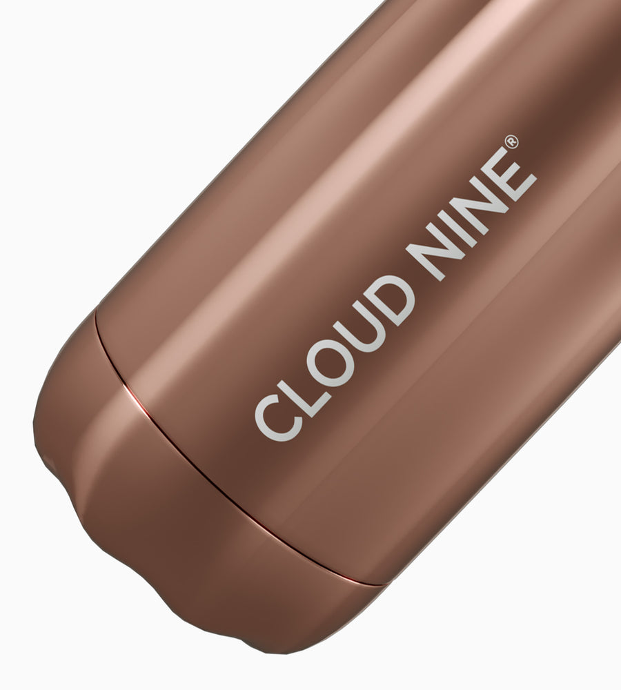 Close up image of lower half of rose gold CLOUD NINE water bottle with white CLOUD NINE branding on white background.